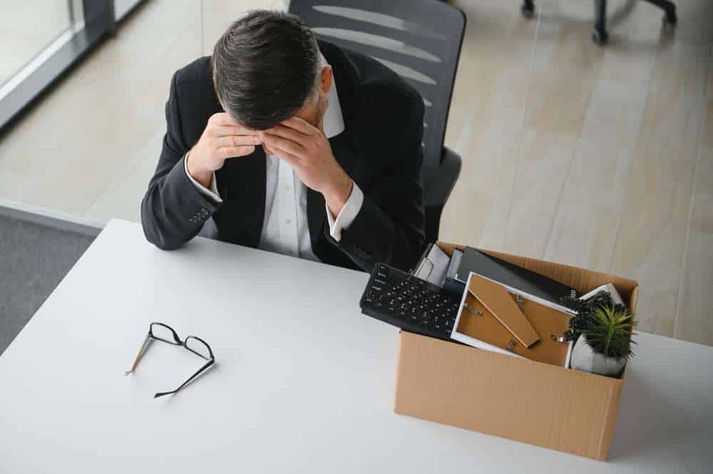 A distressed office worker sitting sadly at his desk, illustrating the emotional impact of an office affair dismissal and workplace relationship consequences.